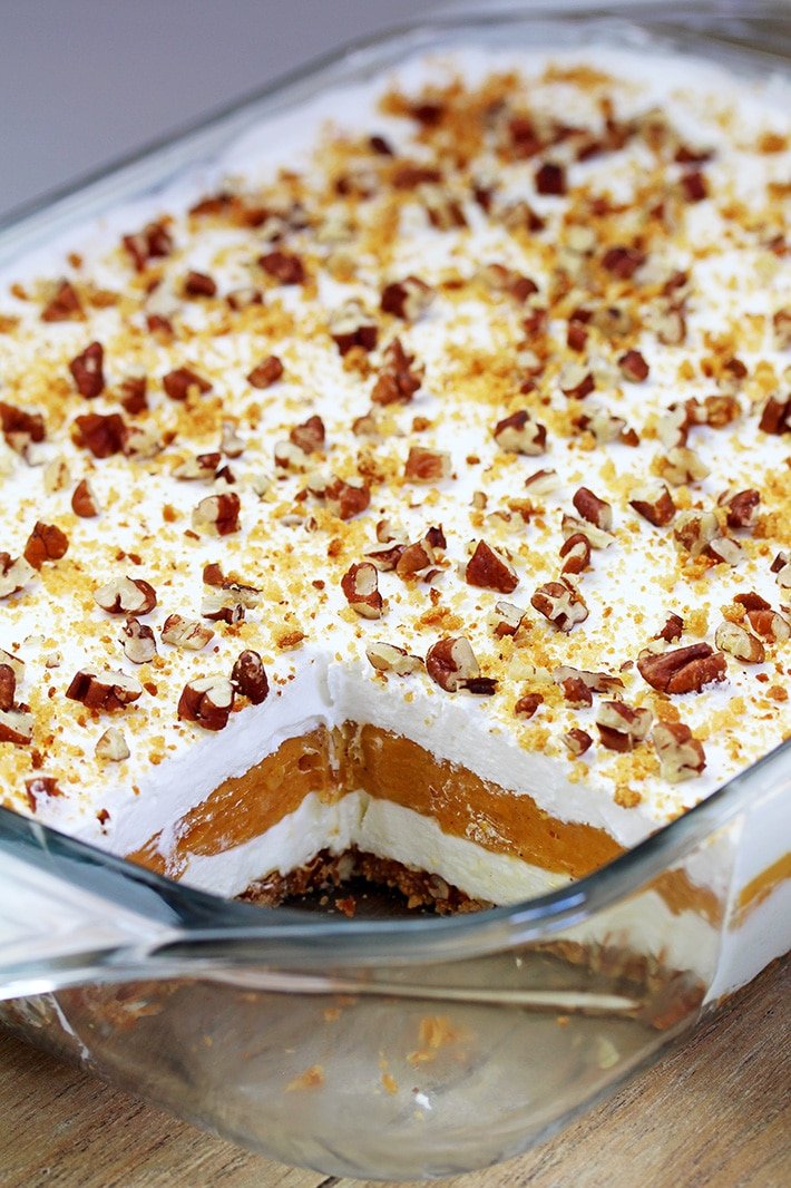 Pumpkin Lush – ce dessert crémeux à la fois léger et délicieux, préparé rapidement, avec de la crème au fromage et des couches de citrouille, et une croûte de biscuits au gingembre, garnie de pacanes hachées et de miettes de biscuits au gingembre, ravira tous les amateurs de citrouille