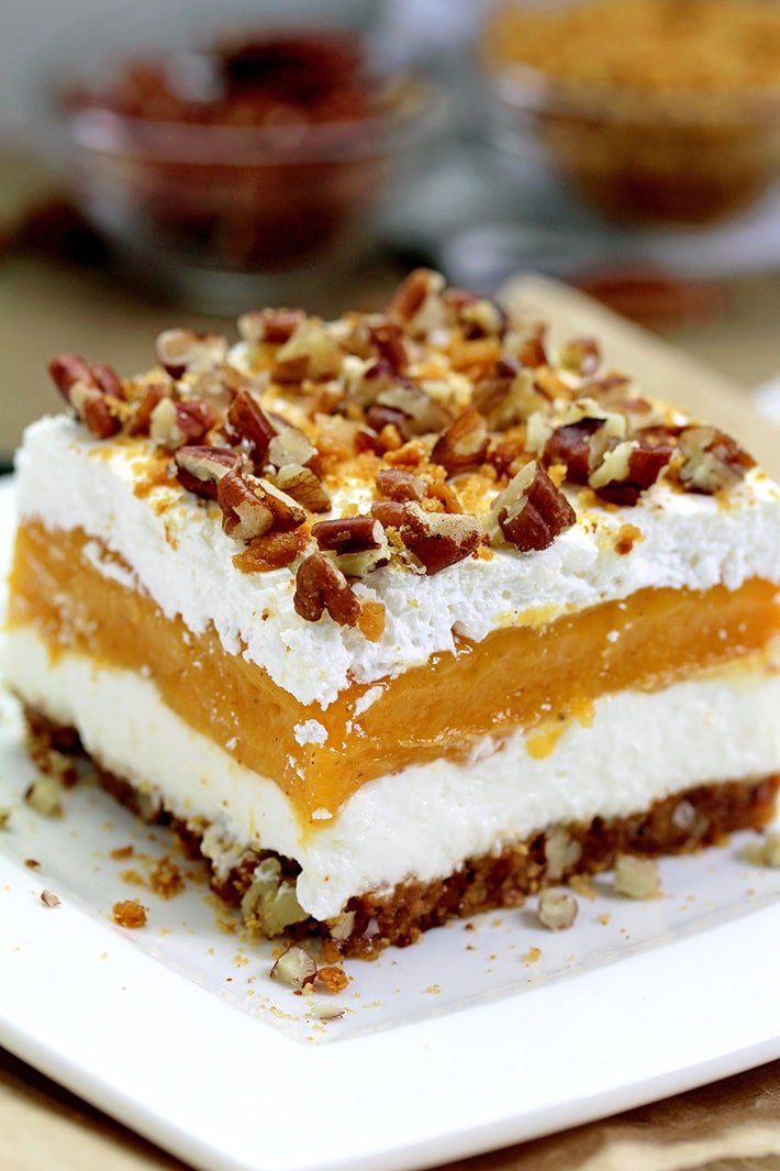 Pumpkin Lush – ce dessert crémeux rapide, léger mais délicieux, avec de la crème au fromage et des couches de citrouille, et une croûte de biscuits au gingembre, garnie de pacanes hachées et de miettes de biscuits au gingembre, ravira tous les amateurs de citrouille.
