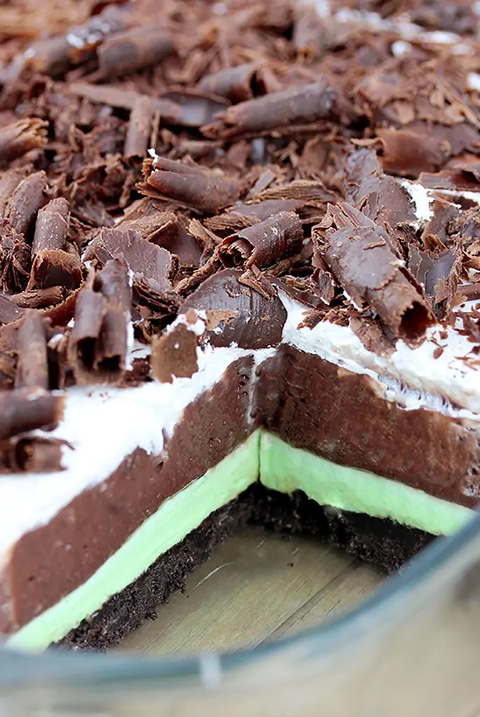 Mint Chocolate Lasagna easy no-bake dessert with layers of Oreo crust, Mint cream cheese, Chocolate pudding, Whipped cream and Chocolate Curls on top.