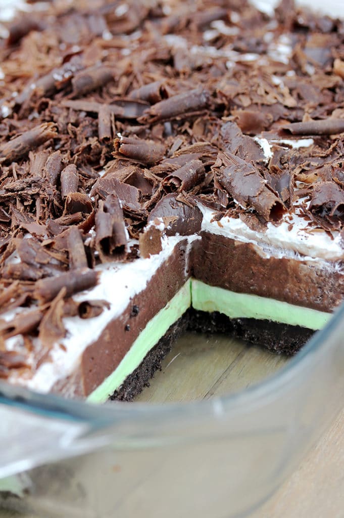 Mint Chocolate Lasagna easy no-bake dessert with layers of Oreo crust, Mint cream cheese, Chocolate pudding, Whipping Cream and Chocolate Curls on top.