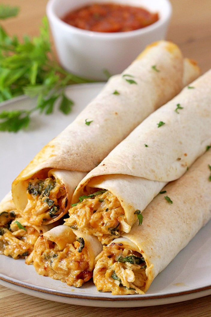 Cream Cheese Chicken Flautas – crunchy tortillas, juicy chicken and melted cheese make an incredible combination. These flautas are made of shredded cooked chicken, cream cheese, cheddar cheese, sour cream, spinach, salsa and different spices, all rolled up in tortillas, then baked or fried and finally served with salsa, guacamole sauce or sour cream. 