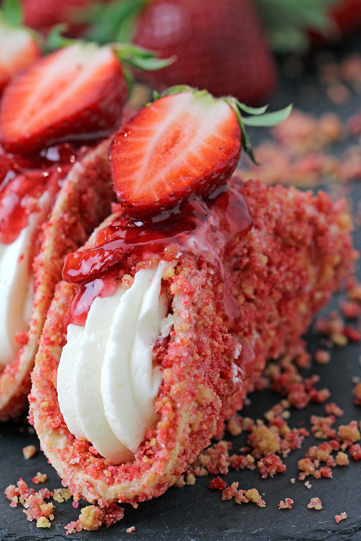 Strawberry Crunch Cheesecake Tacos – crunchy tortilla shell coated in white chocolate and strawberry crunch, creamy cheesecake filling, topped with fresh strawberries and strawberry syrup is a true delight!